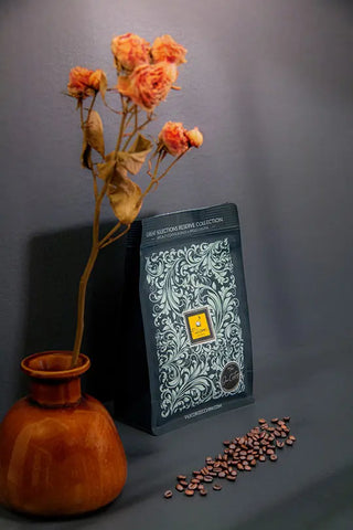 Bolsa de 250 g de café Specialty - rama de rosa seca en maceta de cerámica - granos de café esparcidos.